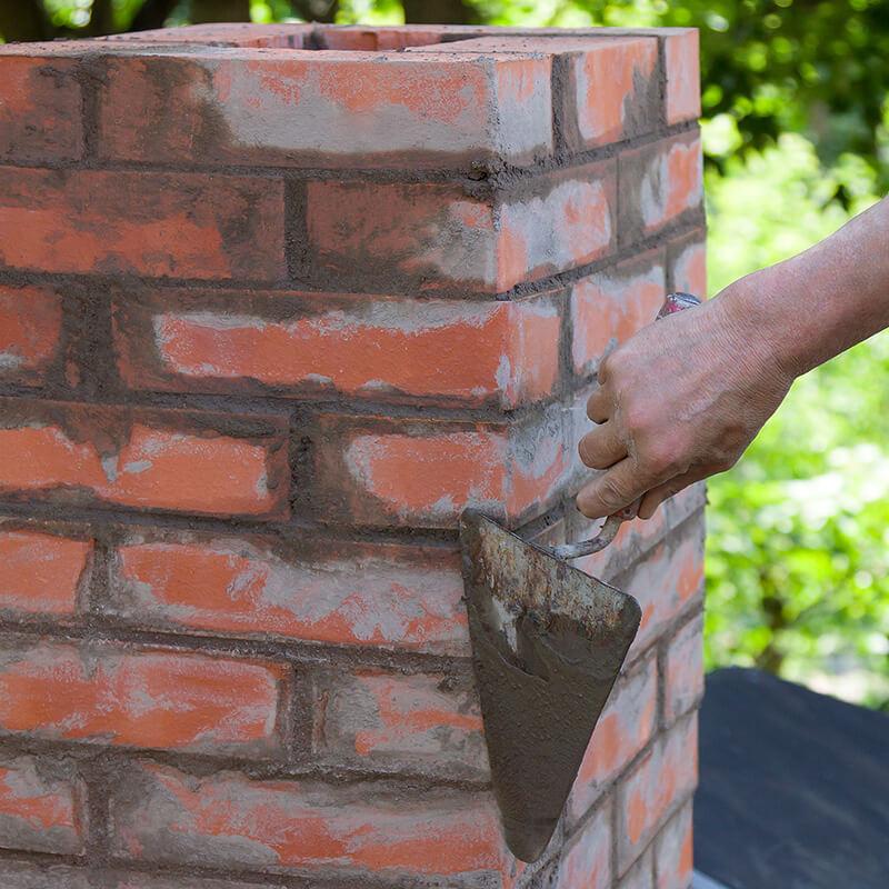Masonry Worker Applying Mortar to a Brick Chimney Wall in Louisville, KY